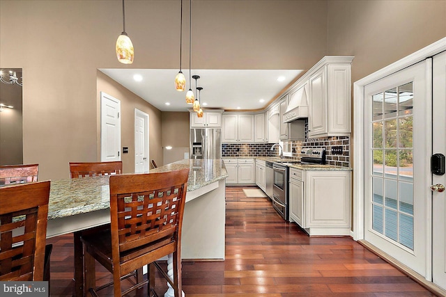 kitchen with white cabinetry, light stone counters, decorative light fixtures, and appliances with stainless steel finishes