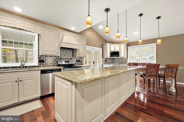 kitchen with custom exhaust hood, stainless steel appliances, dark wood-type flooring, a kitchen island, and hanging light fixtures