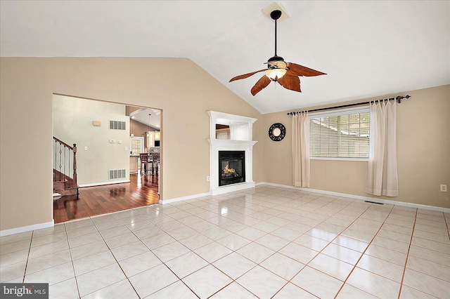 39 Admiral Ave, Ocean Pines, MD 21811 - unfurnished living room featuring a ceiling fan, light tile patterned floors, lofted ceiling, stairs, and a glass covered fireplace