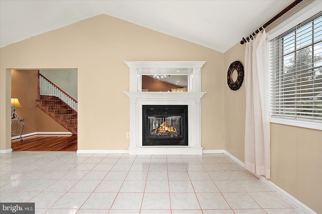 39 Admiral Ave, Ocean Pines, MD 21811 - unfurnished living room featuring vaulted ceiling, stairs, a glass covered fireplace, tile patterned floors, and baseboards