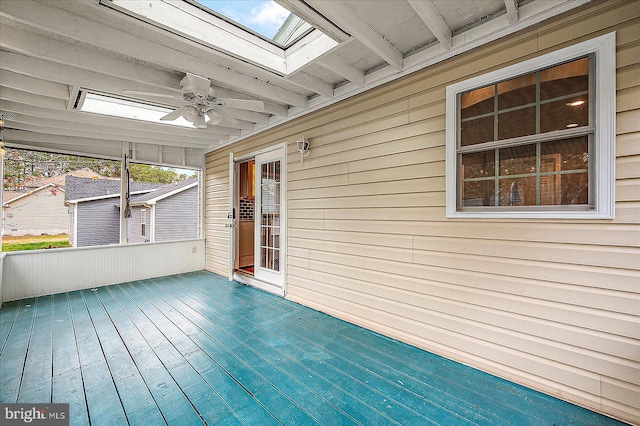 unfurnished sunroom featuring beam ceiling, a skylight, and ceiling fan