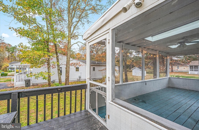 wooden deck with a lawn and a sunroom