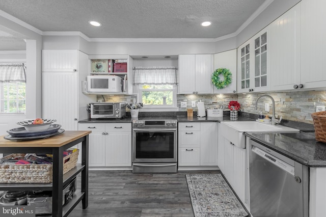 kitchen featuring appliances with stainless steel finishes, dark hardwood / wood-style flooring, white cabinetry, and a wealth of natural light