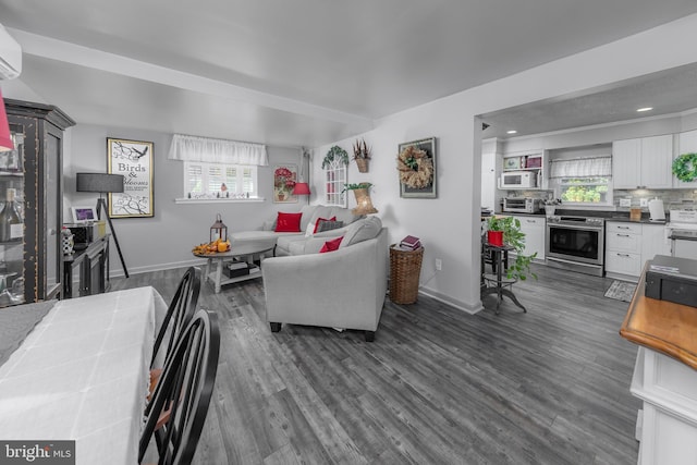 living room featuring a wall unit AC, dark hardwood / wood-style floors, and plenty of natural light