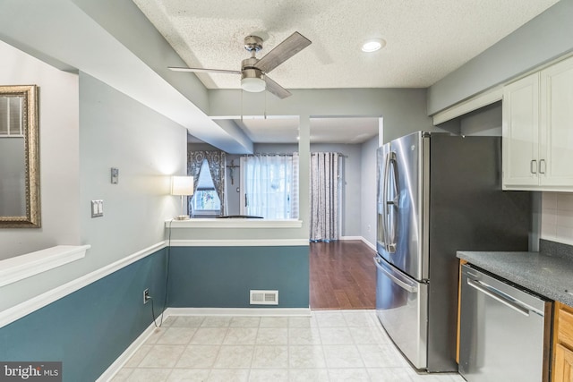 kitchen featuring light hardwood / wood-style floors, white cabinetry, ceiling fan, a textured ceiling, and stainless steel dishwasher