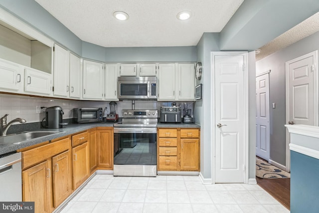 kitchen with stainless steel appliances, white cabinetry, sink, a textured ceiling, and backsplash