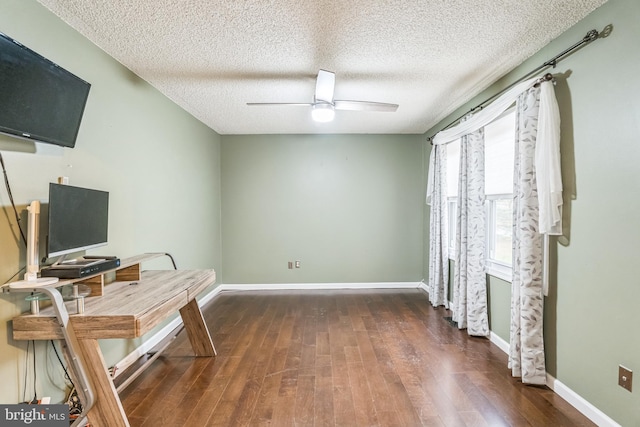 office area with a textured ceiling, dark wood-type flooring, and ceiling fan