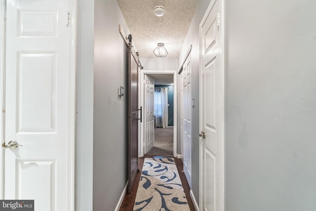 hallway with a barn door and a textured ceiling