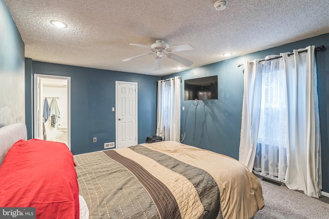 bedroom with carpet floors, a textured ceiling, ceiling fan, and ensuite bath