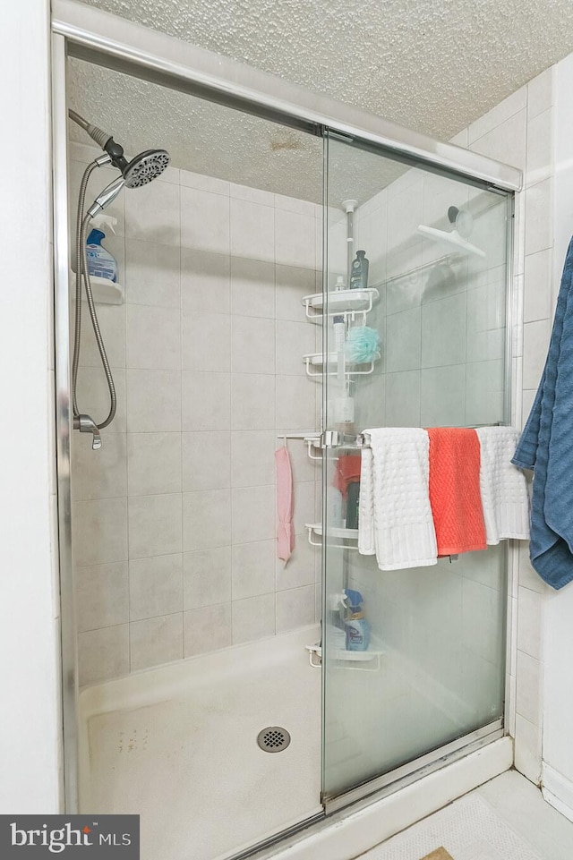 bathroom with a textured ceiling and an enclosed shower