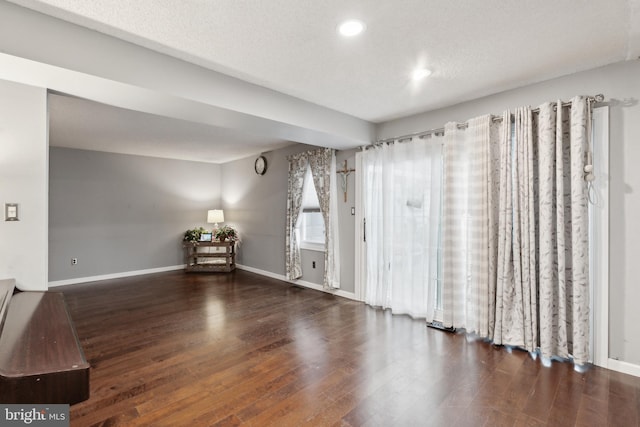 empty room with dark wood-type flooring and a textured ceiling