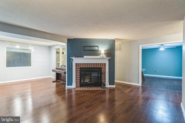 unfurnished living room with dark hardwood / wood-style flooring, a wall unit AC, a textured ceiling, and a fireplace