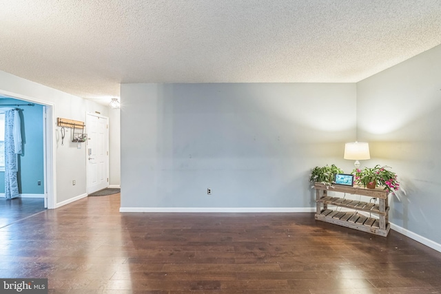 unfurnished room featuring a textured ceiling and dark hardwood / wood-style flooring