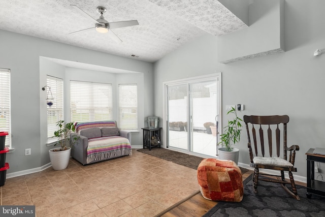 sitting room featuring a textured ceiling, vaulted ceiling, light tile patterned flooring, and ceiling fan