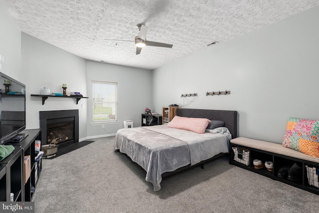 carpeted bedroom with ceiling fan and a textured ceiling