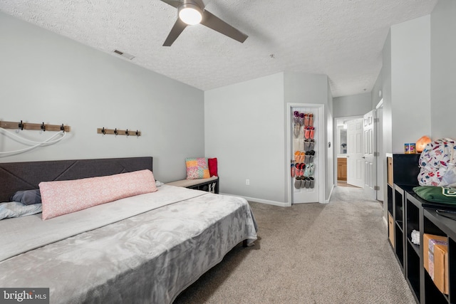 bedroom featuring ceiling fan, light colored carpet, and a textured ceiling