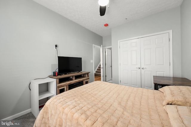 carpeted bedroom with a textured ceiling, a closet, and ceiling fan