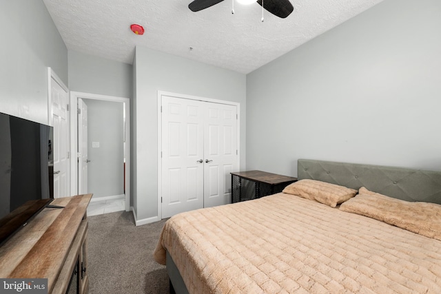 carpeted bedroom with ceiling fan, a textured ceiling, and a closet