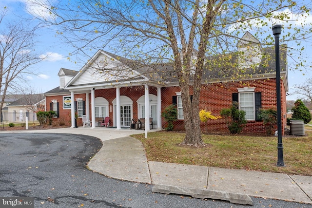 view of front of home featuring covered porch, central air condition unit, and a front lawn