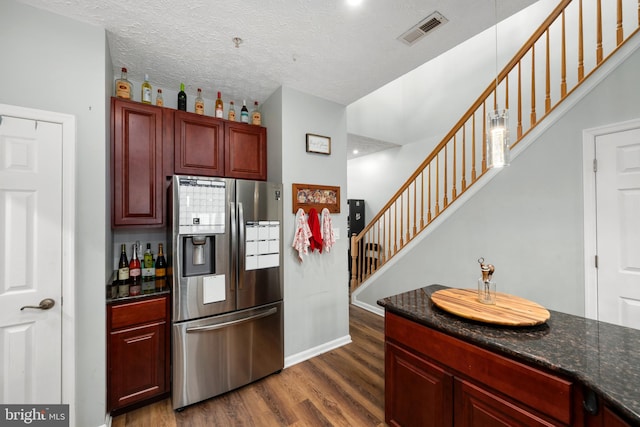 kitchen featuring dark stone countertops, a textured ceiling, dark hardwood / wood-style floors, and stainless steel fridge with ice dispenser