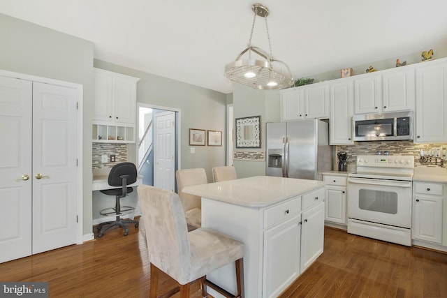 kitchen with dark hardwood / wood-style flooring, white cabinets, stainless steel appliances, and a kitchen island