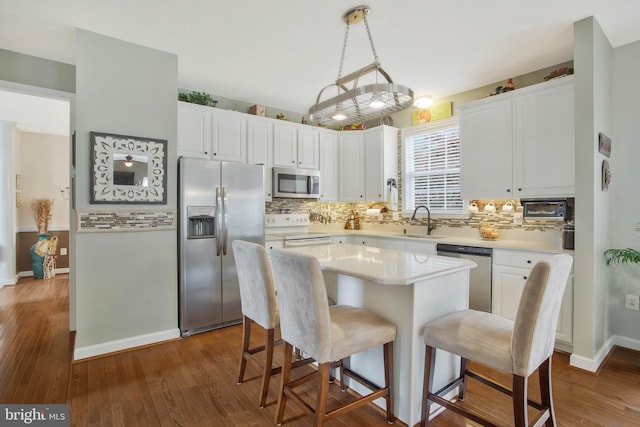 kitchen featuring appliances with stainless steel finishes, white cabinetry, a center island, and dark hardwood / wood-style floors