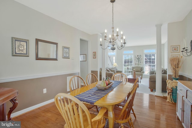 dining space with a chandelier, light hardwood / wood-style flooring, and ornate columns