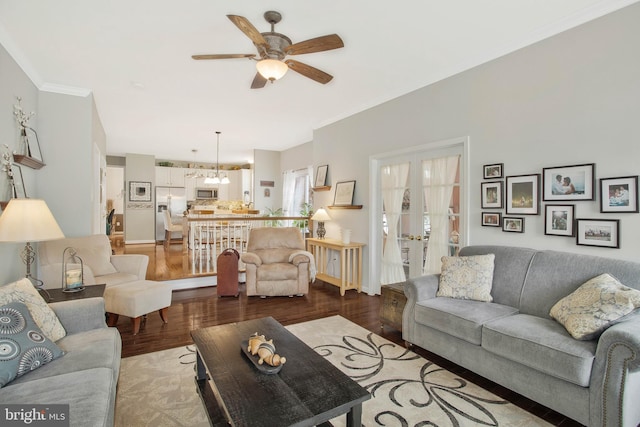 living room featuring french doors, light hardwood / wood-style floors, ornamental molding, and ceiling fan with notable chandelier