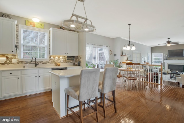 kitchen with white cabinets, hanging light fixtures, sink, dark wood-type flooring, and a center island