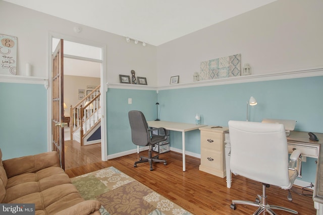 office with hardwood / wood-style floors and track lighting