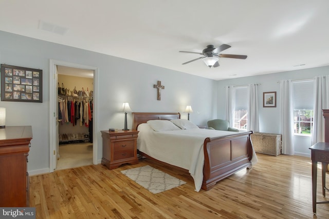 bedroom featuring a closet, a spacious closet, light wood-type flooring, and ceiling fan