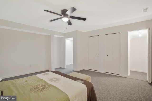 bedroom with two closets, carpet floors, and ceiling fan