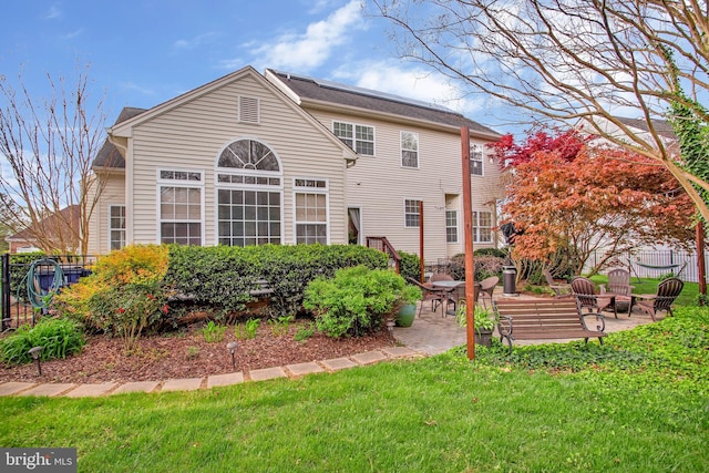 rear view of property featuring a patio and a lawn