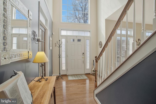 foyer entrance featuring a towering ceiling and light hardwood / wood-style floors