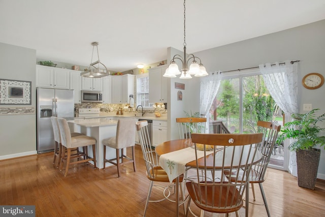 dining area featuring a notable chandelier, sink, and light wood-type flooring