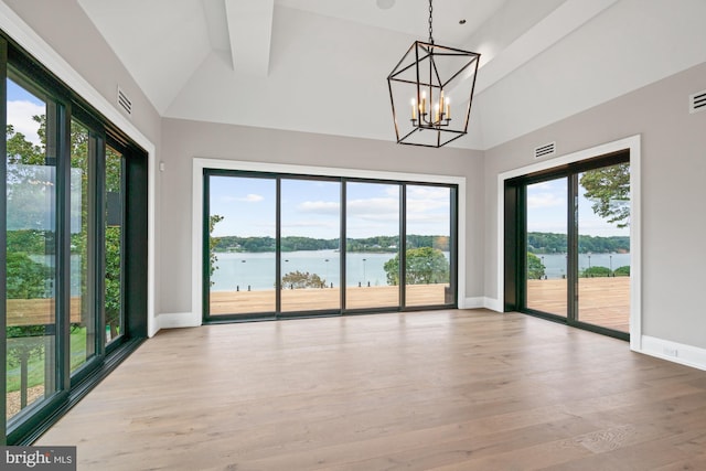 spare room with baseboards, lofted ceiling, wood finished floors, and a water view