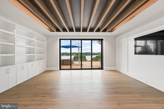 interior space featuring beam ceiling, light wood-style flooring, built in features, and baseboards