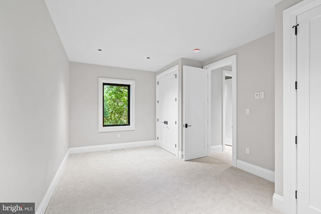 unfurnished bedroom with light colored carpet and baseboards