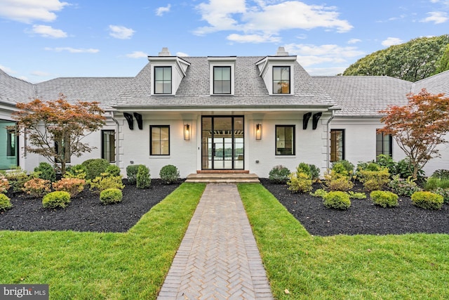 view of front of property with a front lawn, a high end roof, and brick siding