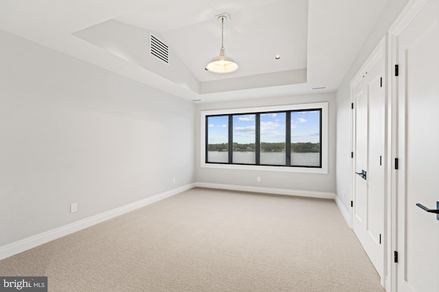 unfurnished bedroom with visible vents, baseboards, a tray ceiling, vaulted ceiling, and light carpet