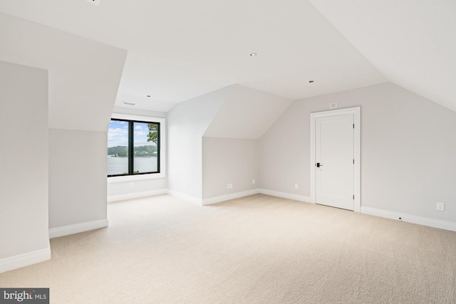 bonus room with lofted ceiling, light colored carpet, and baseboards