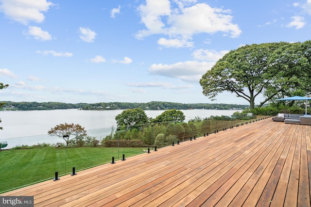 deck featuring an outdoor living space, a yard, and a water view