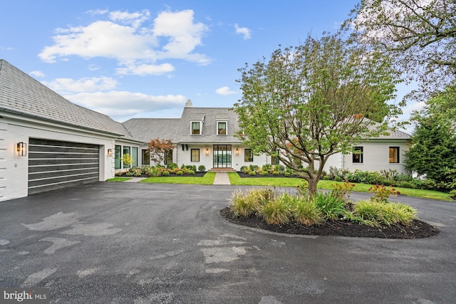 view of front facade with driveway, a front yard, french doors, and a garage