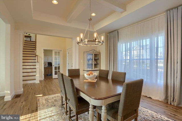 dining area with beamed ceiling, an inviting chandelier, and light wood-type flooring