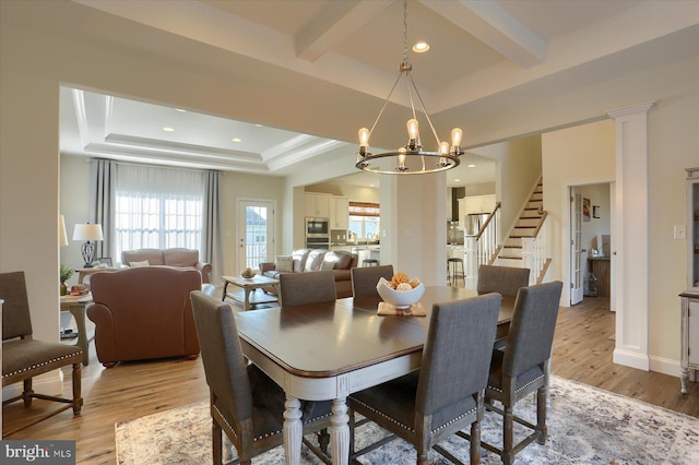 dining room with light hardwood / wood-style floors, a tray ceiling, and a chandelier