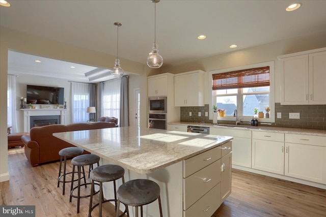 kitchen with white cabinets, backsplash, stainless steel appliances, sink, and a center island