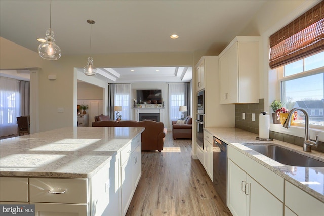 kitchen featuring decorative backsplash, light stone counters, white cabinetry, light hardwood / wood-style floors, and sink