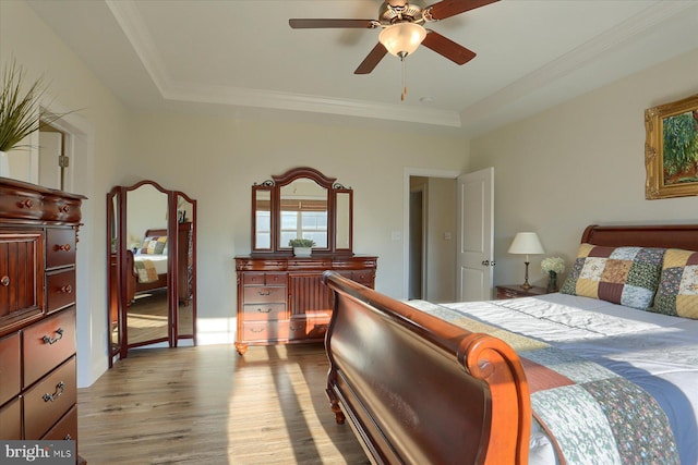 bedroom featuring ceiling fan, a raised ceiling, wood-type flooring, and ornamental molding