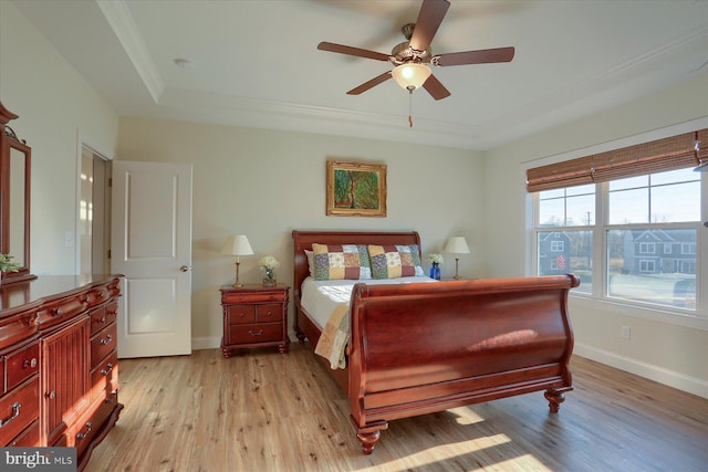 bedroom with ceiling fan, crown molding, a tray ceiling, and light wood-type flooring