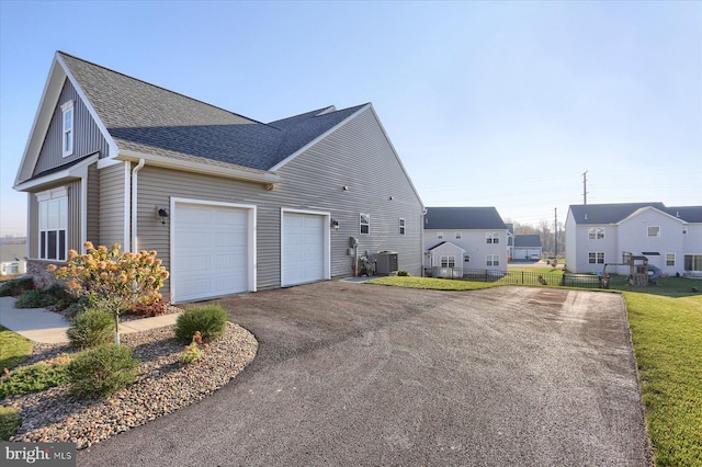 view of side of property with cooling unit, a yard, and a garage